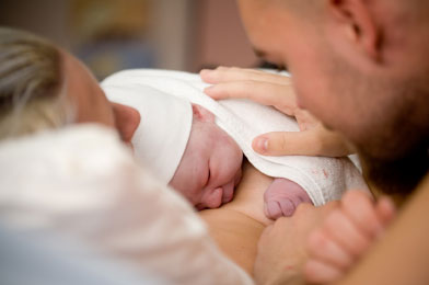 mother and father looking at new born baby