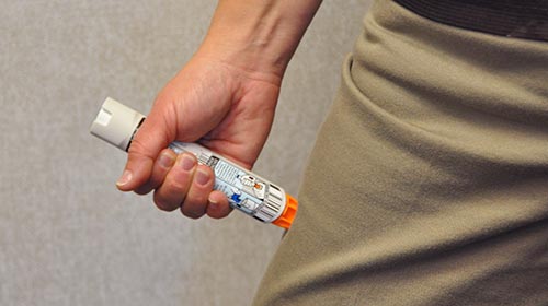 Photo of person administering an Epipen in thigh