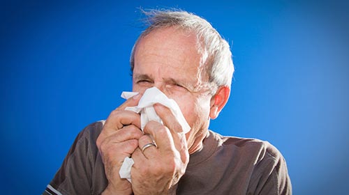 Photo of an elderly person blowing their nose