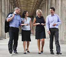 Four people walking together dressed in business atire.