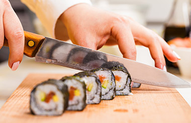 Photo of a knife slicing through a sushi roll