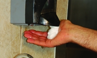 A person getting soap from a soap dispenser. 