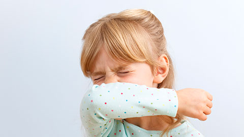 Girl sneezing into her elbow