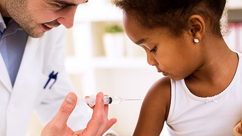 Doctor administering an immunization shot to little girl