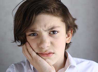 teenager boy with toothache hold his cheek with hand