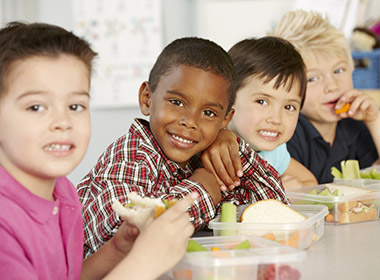 Group Of Elementary Age Schoolchildren Eating Healthy Packed Lunch In Class