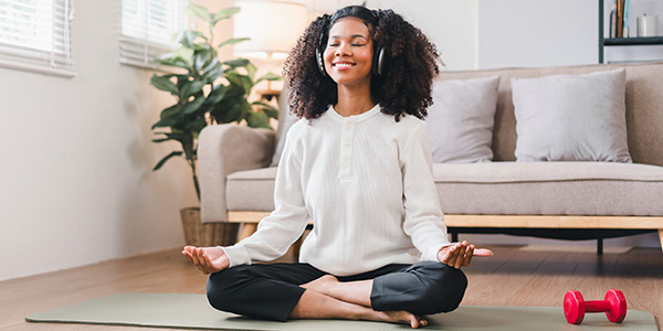 Photo of a young woman smiling while doing yoga at home